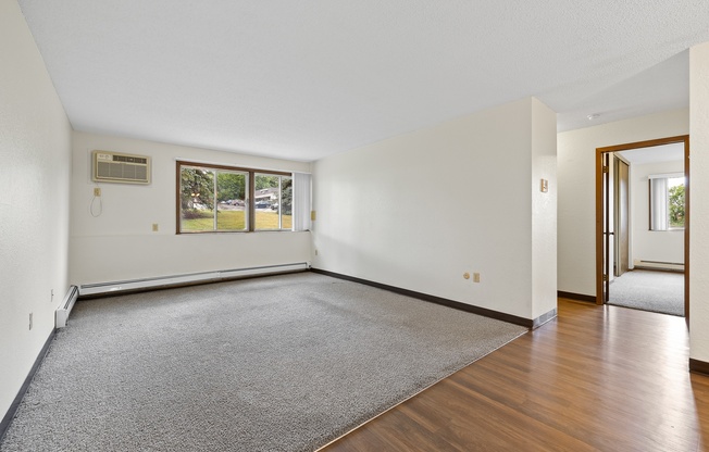 A room with a grey carpet and wooden flooring.