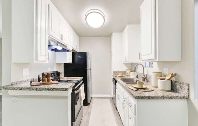 A kitchen with white cabinets and granite countertops.