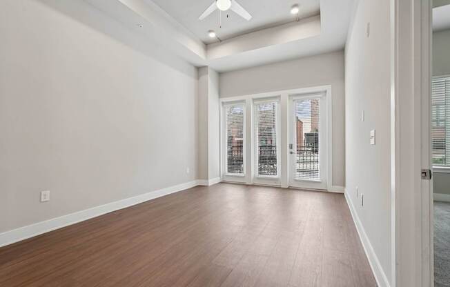 A living room with super high ceiling and tray ceiling, a ceiling fan and many windows with a patio