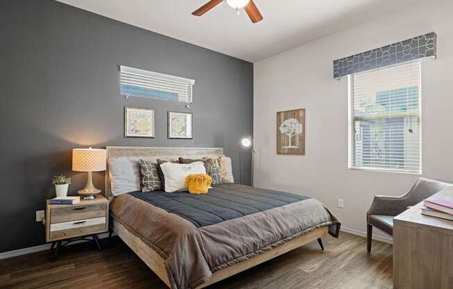 A bedroom with a bed, nightstand, chair, and pictures on the wall.
