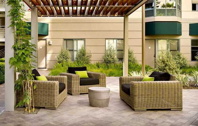 A patio with a wooden roof and wicker furniture.