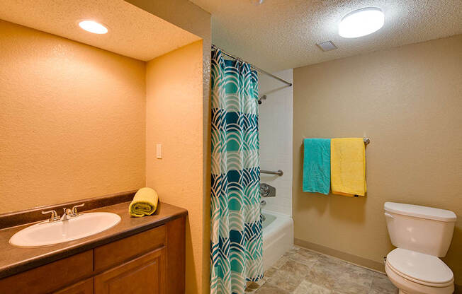 full bathroom with multicolored towels and blue shower curtain