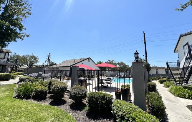 a yard with a pool and a fence and some umbrellas