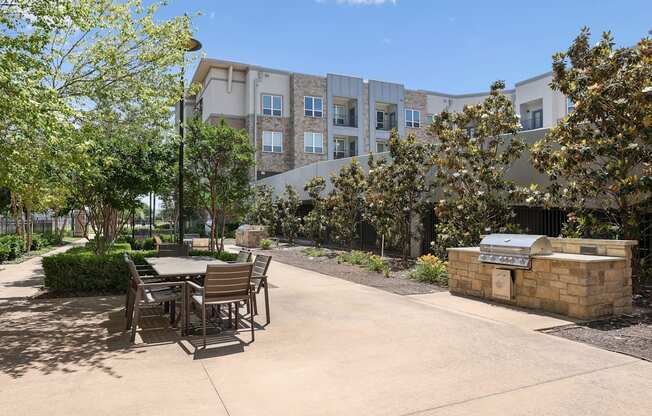 A courtyard with a table and chairs and grilling station at GreenVue apartments in Richardson, TX