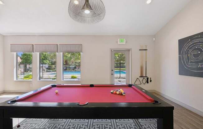 A pool table with a red cloth and white balls is in the center of the room.