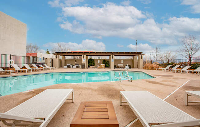 a swimming pool with lounge chairs and a building in the background