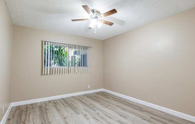 an empty living room with a ceiling fan and a window