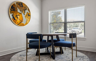 A round artwork hangs on a wall above a table with chairs.