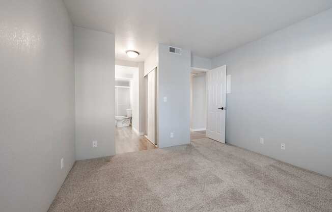 A spacious, empty room with carpeted floor and white walls.