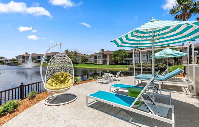 A sunny day at the poolside with a chair, table, and umbrella.