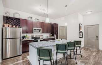 A kitchen with a marble countertop and green chairs.