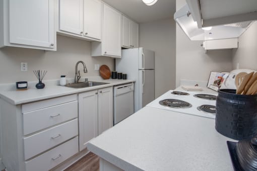 Model apartment kitchen with white cabinets and a white stove and refrigerator