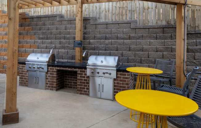 a patio with two stainless steel appliances and a table with yellow chairs
