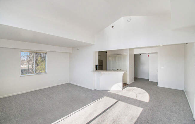 A spacious living room with a cathedral ceiling and a window at West Hampton Park Apartments in Elkhorn, NE 68022