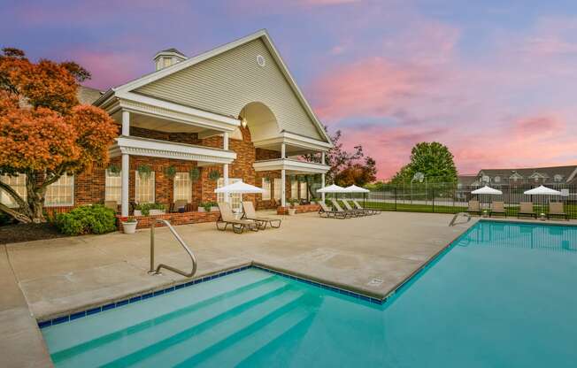 Outdoor swimming pool and pool house, sunset in background