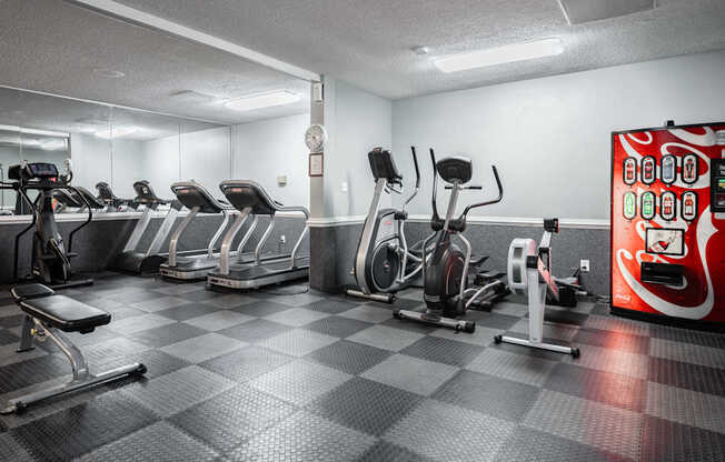 A gym with a variety of exercise equipment including treadmills, stationary bikes, and weight machines.