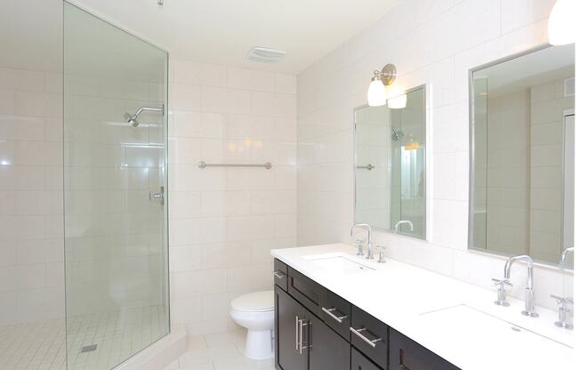 2 bedroom bathroom with dark cabinet, white vanity, mirror and stand up shower with white tile. at York House, Saint Louis, 63108