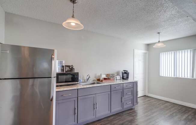a kitchen with gray cabinets and a stainless steel refrigerator
