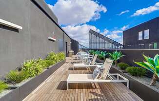 A modern balcony with wooden flooring and white lounge chairs.