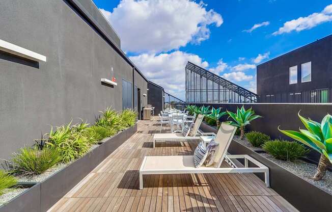 A modern balcony with wooden flooring and white lounge chairs.