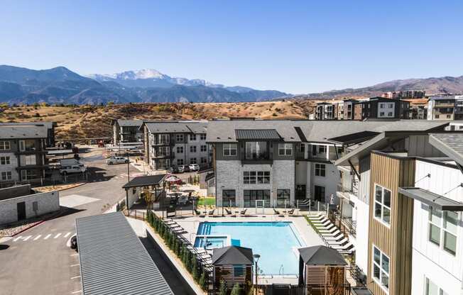 an aerial view of an apartment complex with a pool and mountains in the background