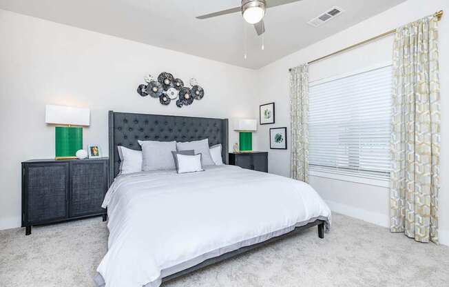 A bedroom with a large bed and a ceiling fan.