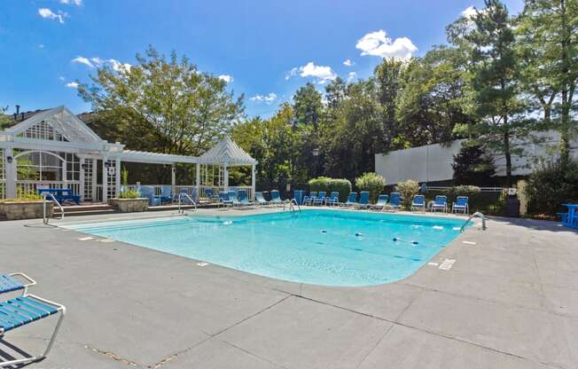 a resort style pool with blue chairs around it and a white gazebo