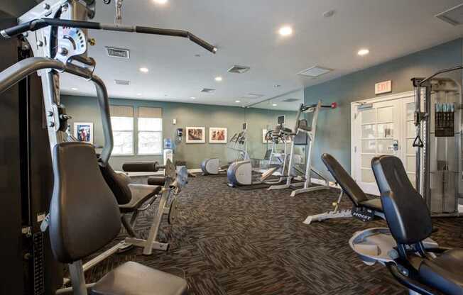 A gym with a variety of equipment including treadmills, weights, and exercise machines.