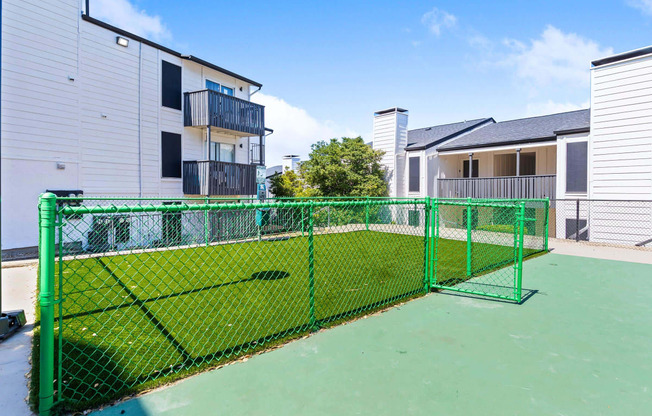 the private tennis court is fenced in with a green fence