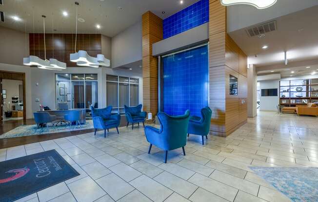 a lobby with blue chairs and a blue waterfall in the center