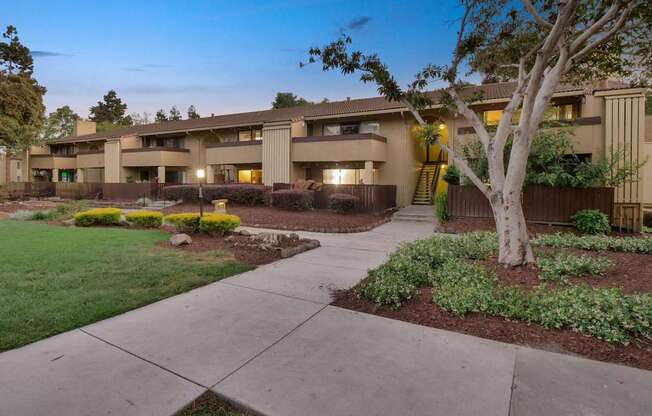 a building with a sidewalk and trees in front of it at Summerwood Apartments, Santa Clara, 95050