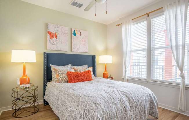 A bedroom with a bed, two lamps, and a painting on the wall.