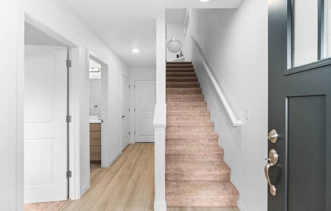 a staircase in a home with white walls and wood floors