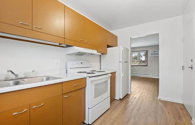 A kitchen with white appliances and wooden cabinets.