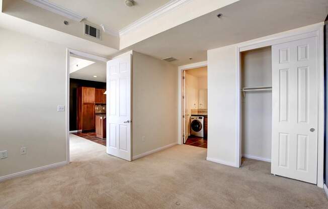 A room with white walls and a carpeted floor with a washing machine in the corner.