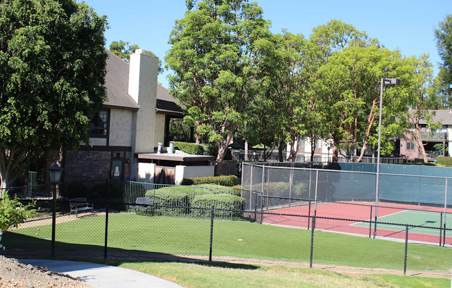 A tennis court is surrounded by a black fence.