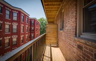 a balcony with a wooden railing and a brick building in the background
