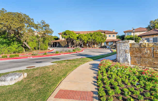 A residential street with houses on both sides and a sidewalk in the foreground. at Bridge at Heritage Woods, Texas, 78753