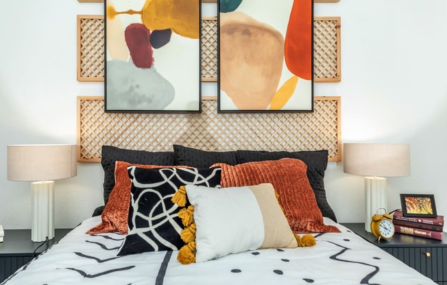 a bedroom with a bed with pillows and artwork on the wall