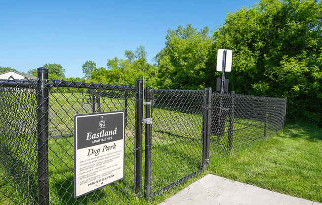 a fence with a sign on it in front of a dog park