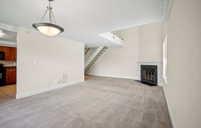 A large, empty room with a carpeted floor and a fireplace.