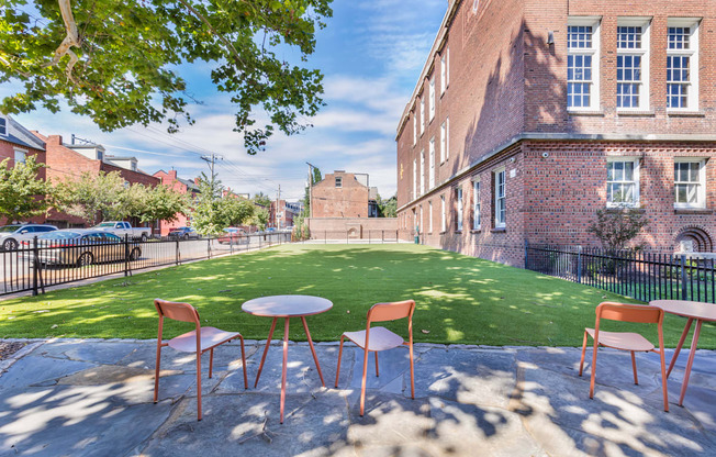 a courtyard with a table and chairs and a green lawn