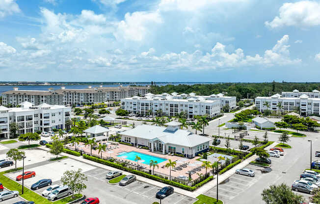 A large white resort with a pool and a parking lot.