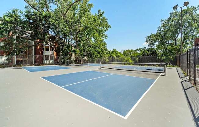 A tennis court surrounded by trees and a fence.
