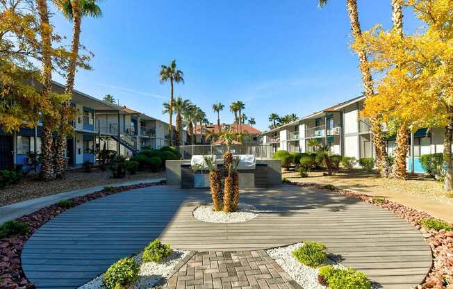 A courtyard with a fountain surrounded by palm trees and buildings.