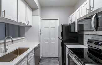 a kitchen with white cabinets and black appliances