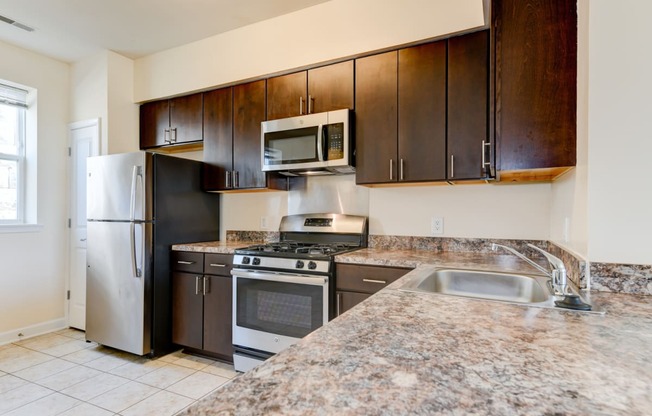 kitchen with espresso cabinetry, breakfast bar and stainless steel appliances at sheridan station south townhomes in washington dc