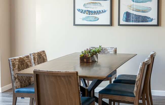 a dining room with a wooden table and chairs and two fish artwork on the wall