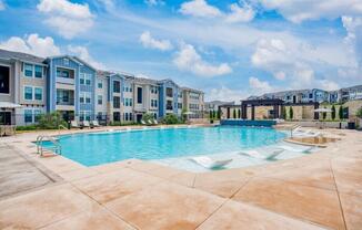 a large swimming pool with an apartment building in the background  at Edge and Stone, Texas