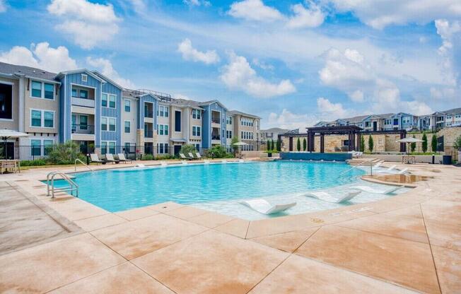 a large swimming pool with an apartment building in the background  at Edge and Stone, Texas